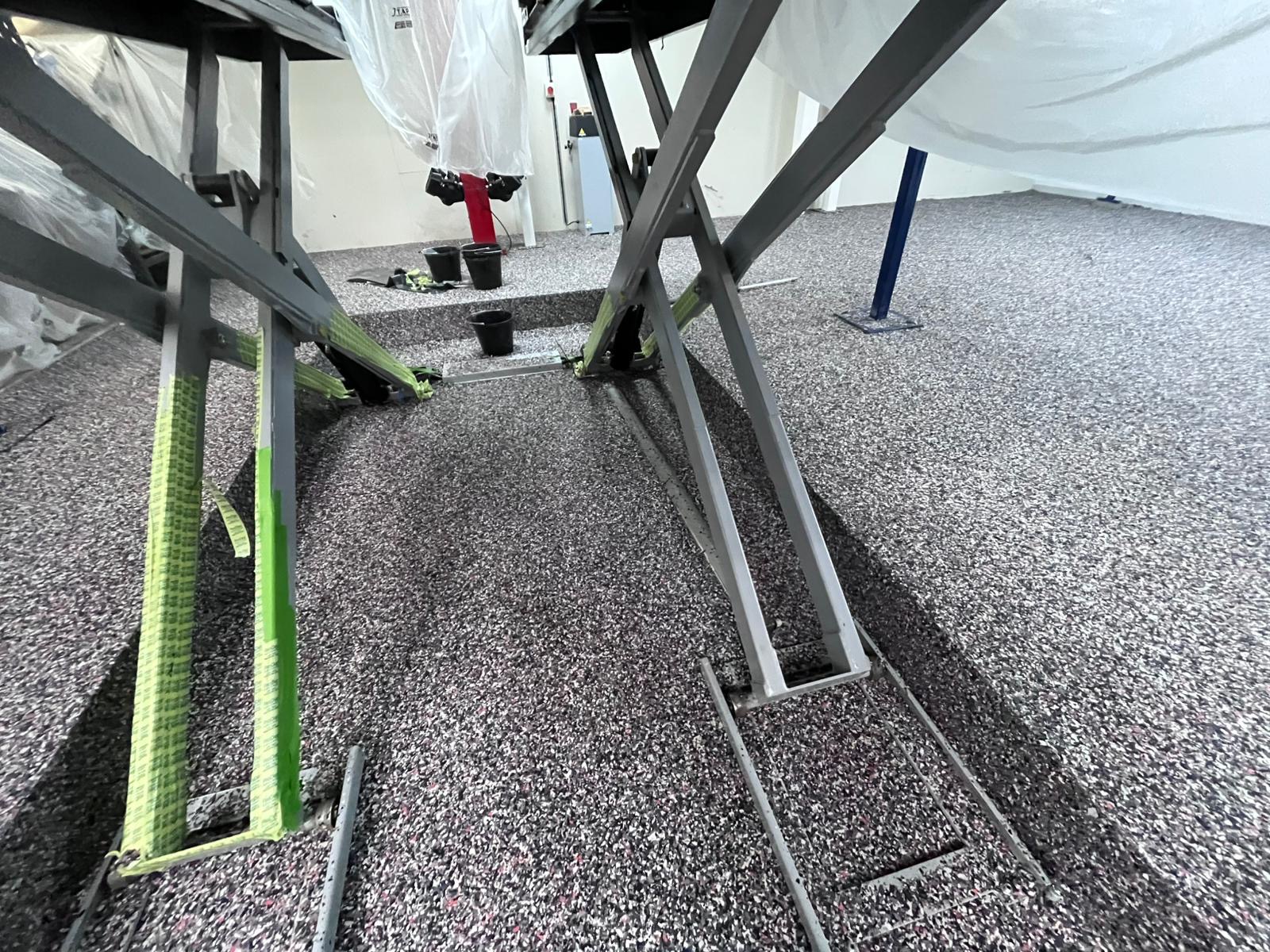 Garage flake flooring installation in progress around vehicle lifts