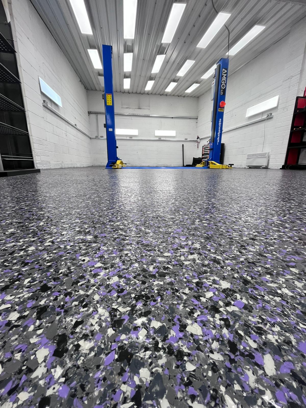 Heavy-duty commercial resin flooring with purple flake in a vehicle lift bay